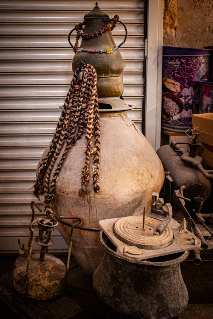 Antique pots and artifacts arranged in front of a metal shutter, showcasing vintage aesthetics and traditional craftsmanship.